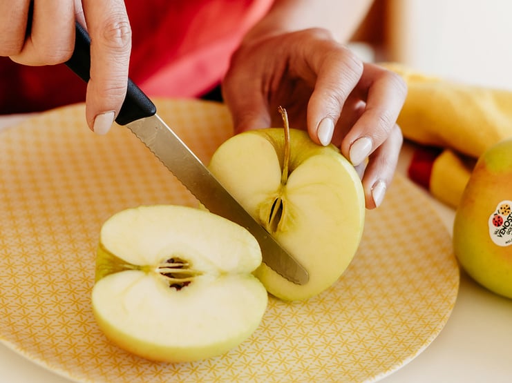 Mele rosse mature nel piatto con un coltello. taglia una mela prima di  mangiare per seguire la dieta